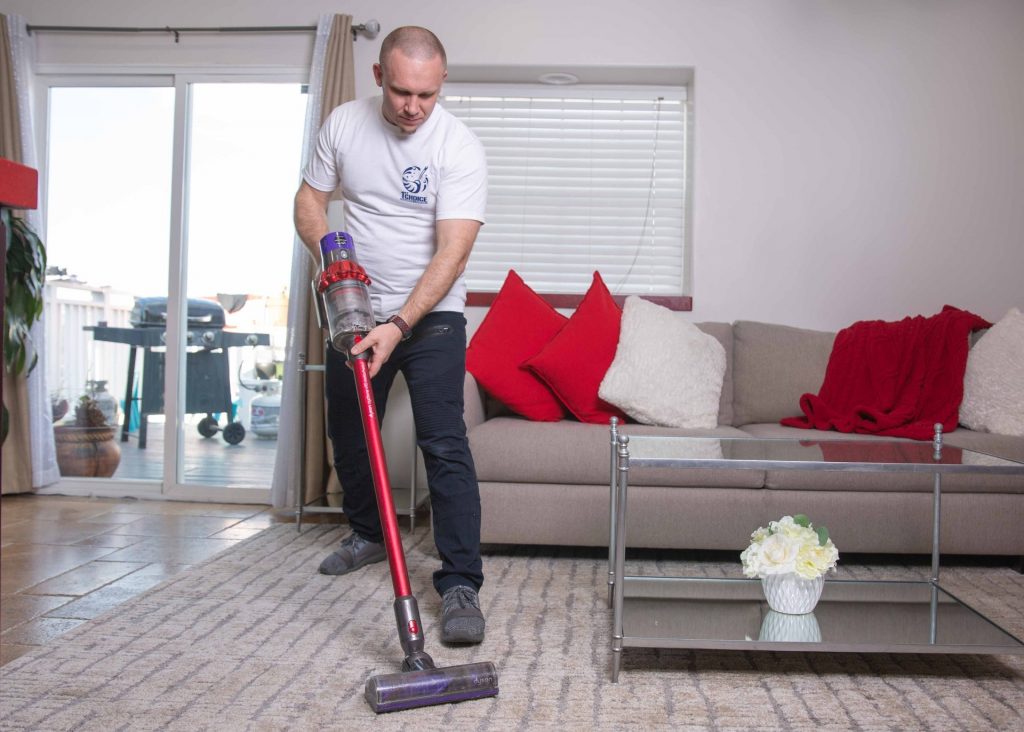 young man vacuuming carpet