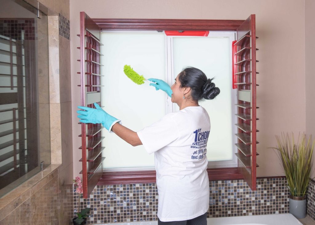 women dusting blinds in a bathroom
